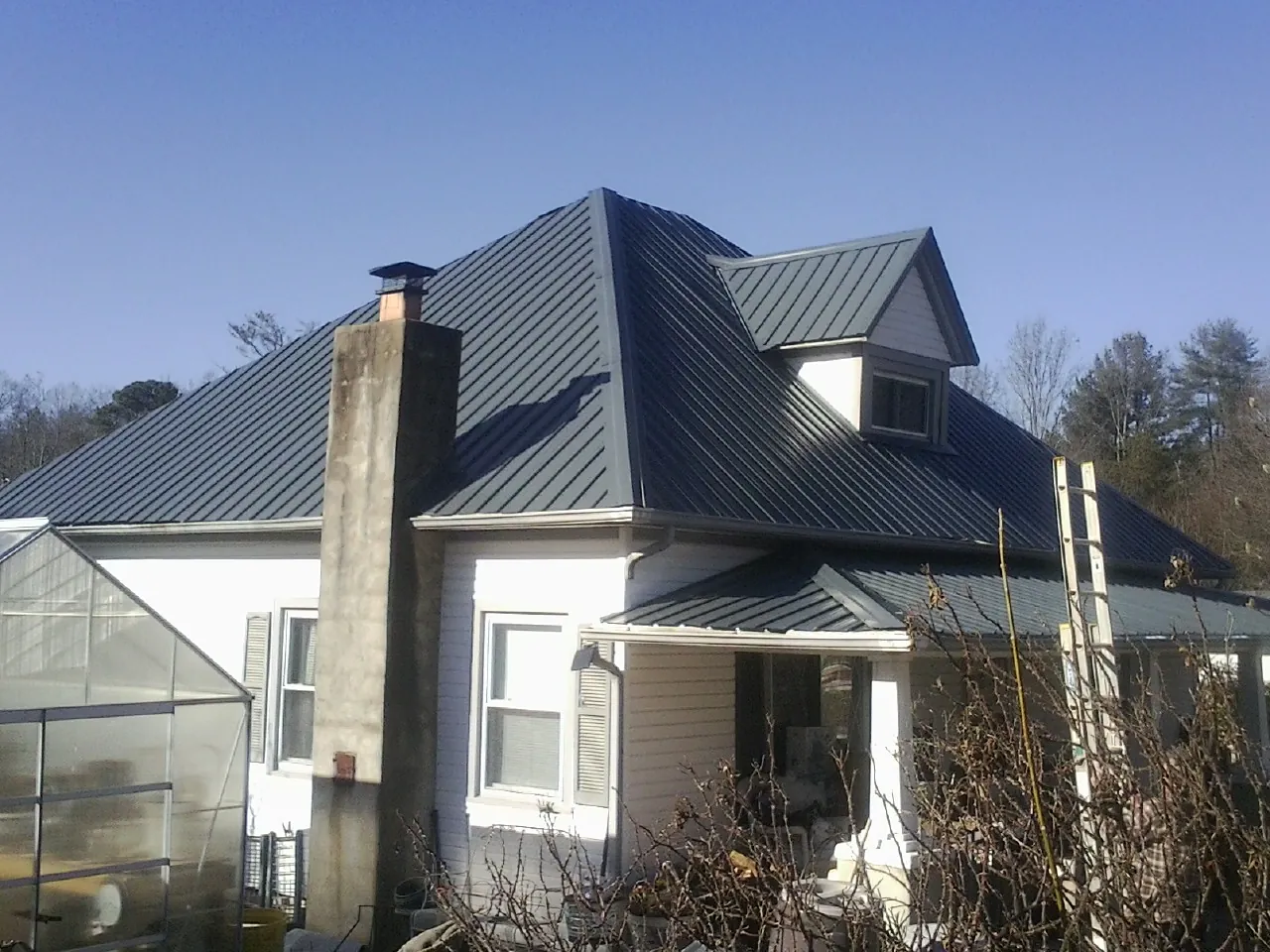 Dark blue standing seam metal roof on a white farmhouse with dormer — Slate & Tile Roof Repair by Roofing Brothers in Molalla