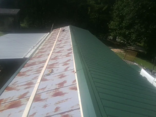 Old rusted panels beside newly installed green metal roofing — Wind Damage Roof Repair by Roofing Brothers in Molalla