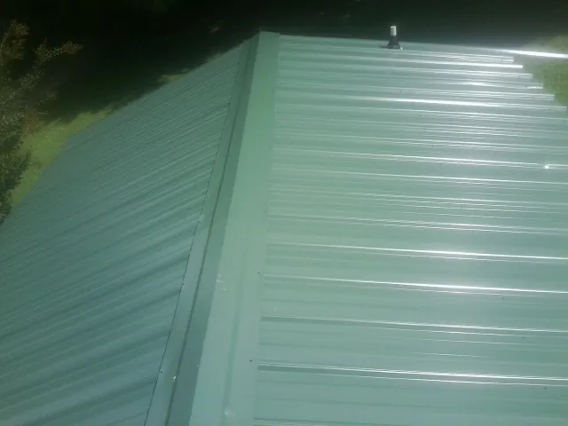 New green metal panels meeting at the ridge of a roof — Flat Roof Repair work by our crew in Molalla