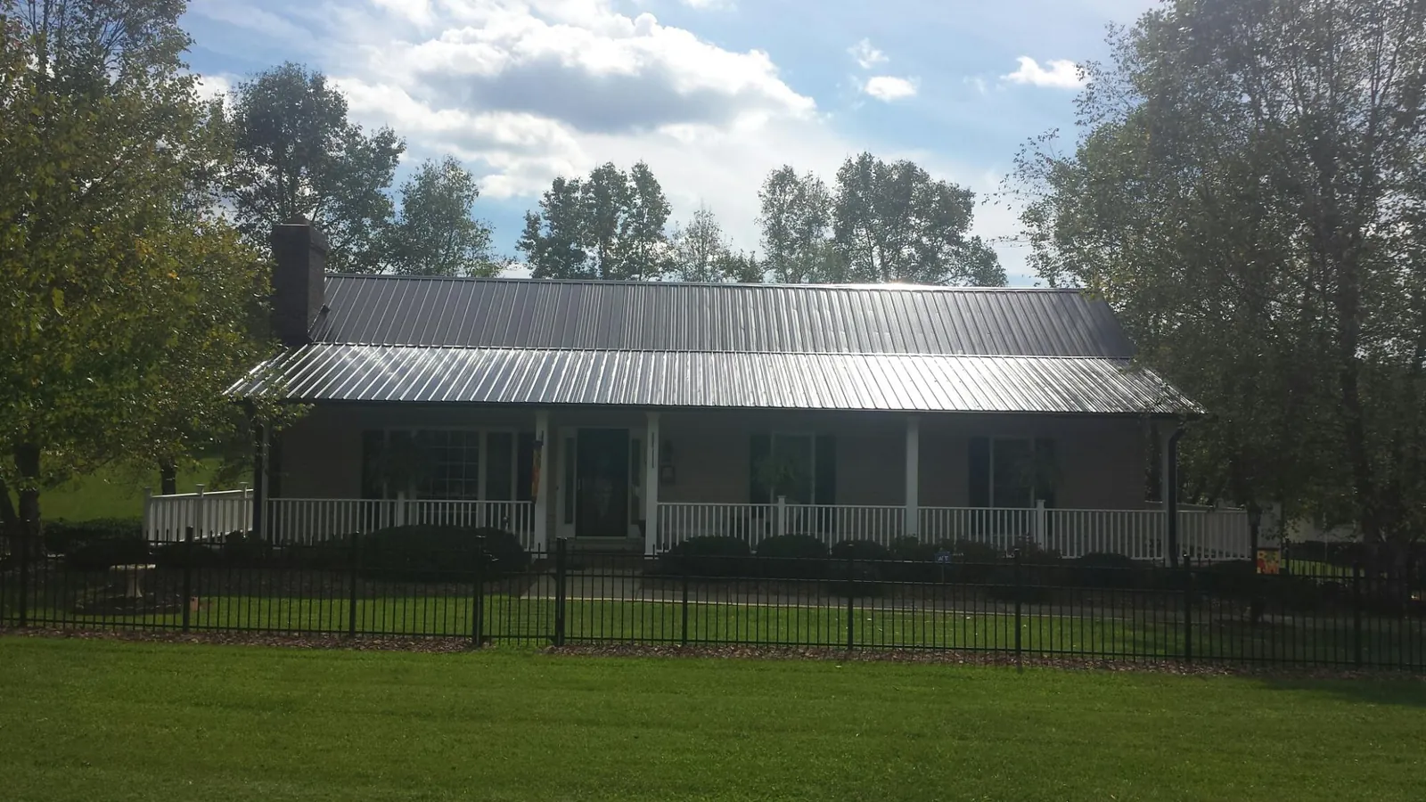 Gray metal roof on a brick ranch with a full width front porch — Gutter Guard Installation work by our crew in Molalla