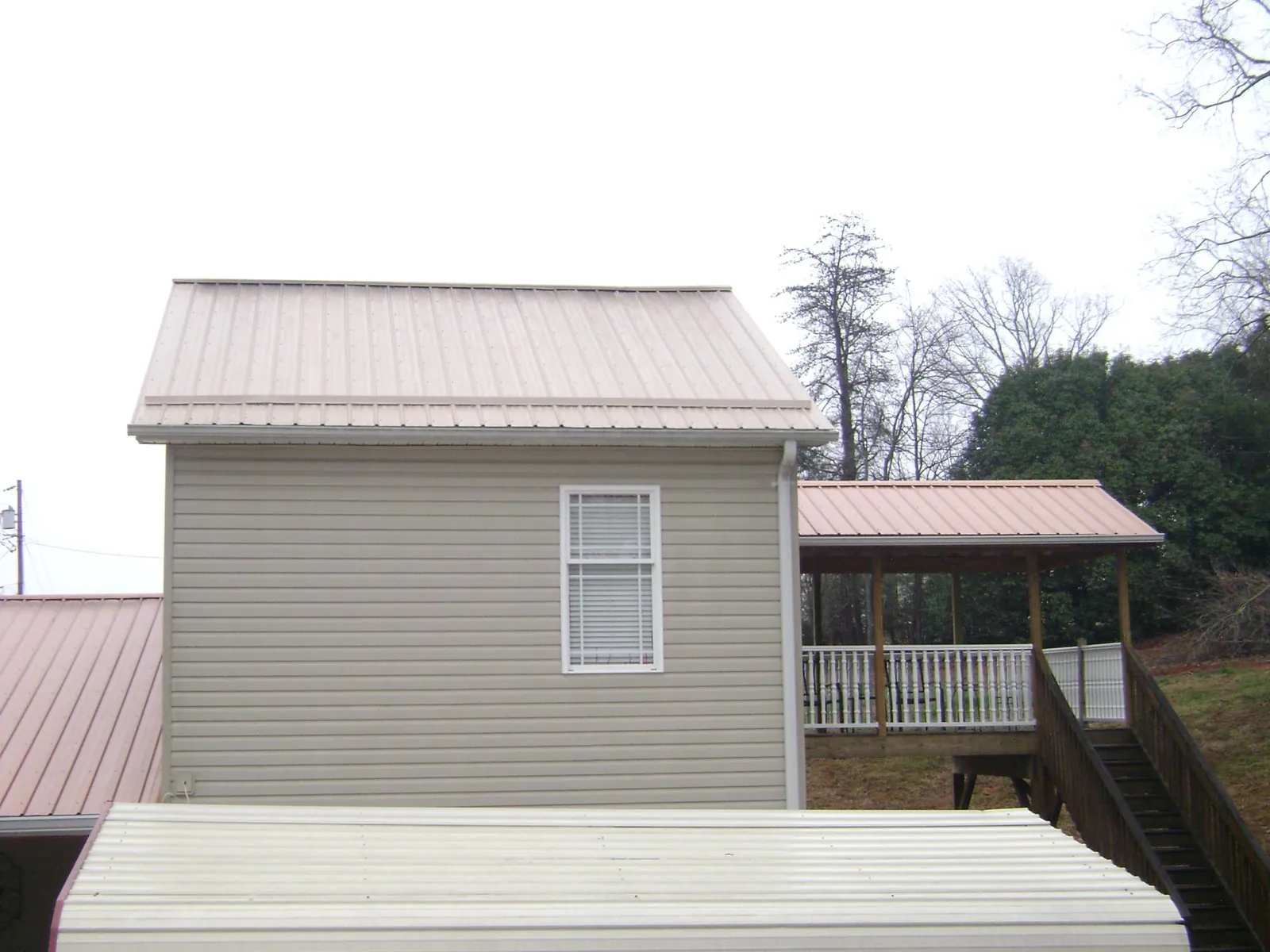 Tan metal roofs on a two story addition and attached porch, from a Roof Replacement job in Molalla