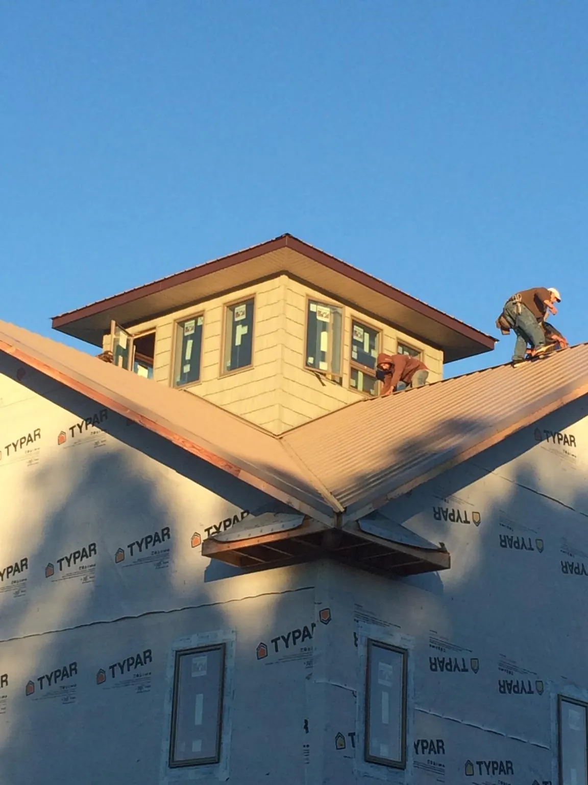 Roofers working around a rooftop cupola on a new metal roof at sunset — Roof Waterproofing in Molalla by Roofing Brothers